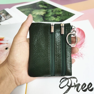 Detail of dark green genuine leather coin purse with three zipper compartments and key ring