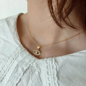 Close-up of golden evil eye necklace with white cubic zirconia on a model's neckline