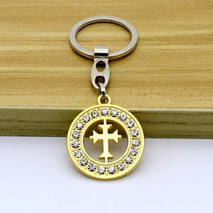 Golden cross pendant keychain with micro-pave crystals on a minimalist wooden surface