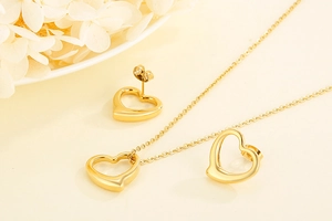 Detail of gold hollow heart necklace and earrings set on a minimalist elegant background