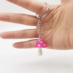 Close-up of a colorful resin mushroom keychain with white dots and silver metal ring