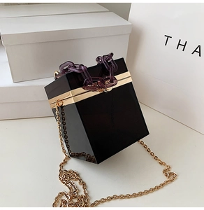 Detail showing black acrylic box bag with purple chain handle and gold metal frame