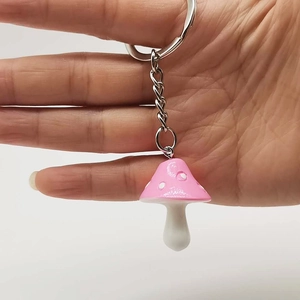 Detailed view of a handmade pink resin mushroom keychain with white dots and silver ring
