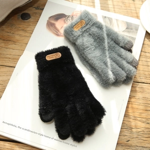 Close-up of black and grey knit touchscreen gloves with bear leather labels on wood