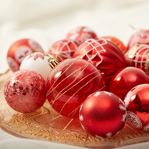Red and white Christmas balls with glitter and snowflake patterns on amber glass tray