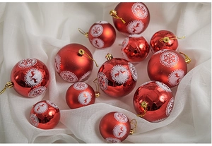 Detail of red Christmas baubles with white reindeer and snowflake motifs on fabric