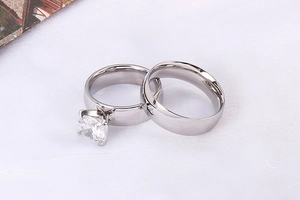 Detail view of silver stainless steel couple rings with six-prong set cubic zirconia stone