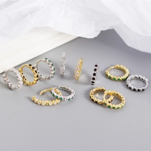 Detail of S925 sterling silver huggie earrings with cubic zirconia in gold and silver finish