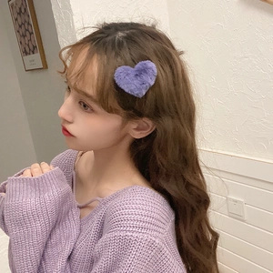 Cute purple plush heart-shaped hair clip worn on a young woman's side hair