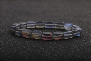 Macro shot of moonstone bead bracelet with iridescent glow on textured black surface