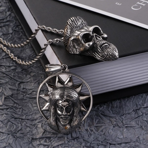 Detailed view of bearded skull and halo face stainless steel pendants on a book