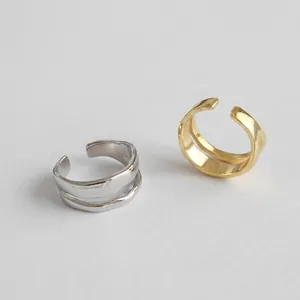 Macro detail of irregular wave double-layer open rings in gold and silver metal finishes