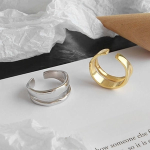 Macro detail of irregular wave double-layer open rings in gold and silver metal finishes