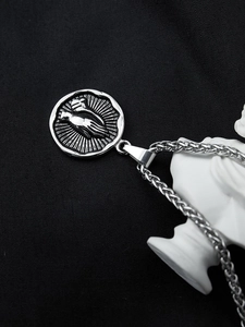 Detailed silver praying hands pendant with sunbeam design on black fabric with statue