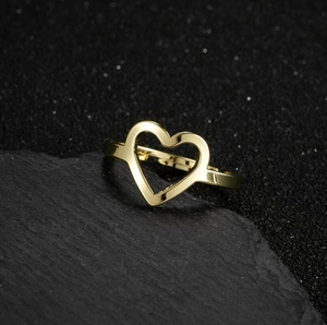 Minimalist gold heart-shaped stainless steel open ring on a textured dark stone background