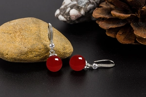 Macro detail of red agate drop earrings with sparkling zircon on a natural stone base