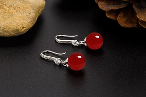 Detailed shot of red agate beaded earring with zircon inlay and silver hook accents