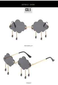 Detail of cloud-shaped gray sunglasses with gold frame and purple teardrop charms