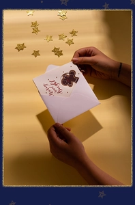 Close-up of hands pulling a gingerbread man Christmas card from an envelope