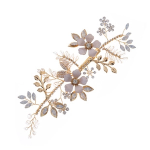 Close-up of golden bridal hair comb with pink flowers, silver leaves, and pearls