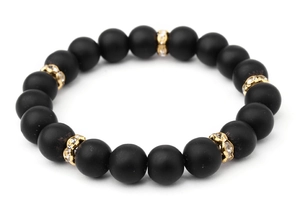 Detailed macro shot of matte black onyx beads with gold rhinestone spacers on elastic cord
