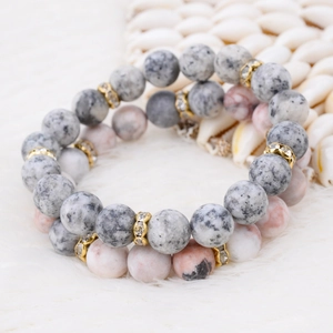 Detail of natural stone beads with crystal-encrusted gold spacers on white plush background