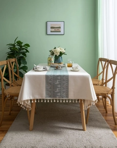 Detail of beige cotton linen tablecloth featuring green reindeer ribbon and tassel edges