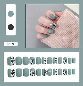 Macro view of 24pcs matte green and cow print press-on nails set with varied sizes