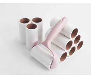 Pink lint roller handle and ten white adhesive paper refills on a clean background