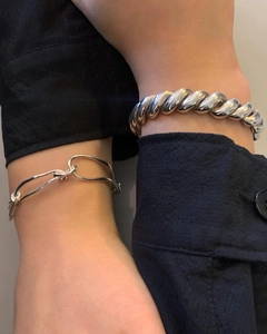 Detail of silver twisted rope cuff and irregular link bracelet on a woman's wrist