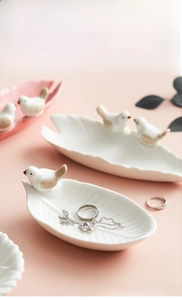 Detail of bird figurine on leaf-shaped ceramic jewelry tray with ribbed texture