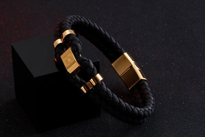 Detail of double-layer black leather bracelet with golden steel cross clasp