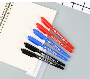 Close-up of dual-tip oil-based markers in red, blue, and black on a grid notebook