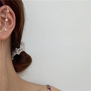 Detail view of gold ear cuff with zircons and pearl hair clip on model side profile