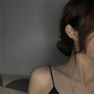 Detail of gold ear cuff with white zircons worn on earlobe for a minimalist jewelry look
