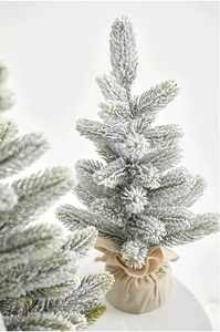 Detailed close-up of a snow-flocked mini Christmas tree with a rustic burlap base wrap