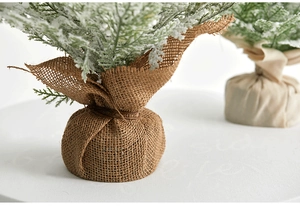 Detail of mini flocked Christmas trees with faux snow and rustic burlap wrapped bases
