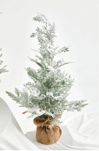 Macro shot of miniature snowy cedar tree with thick white flocking and burlap base