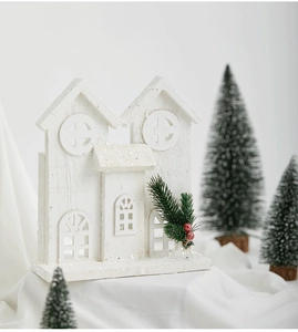 Close-up of white wooden Christmas house with pine needles and berries decor