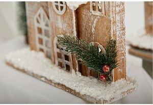 Detail of wooden Christmas house with artificial snow, pine needles, and red berries