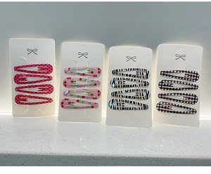 Detail view of 16 metal snap hair clips featuring polka dot, cherry, and zebra patterns