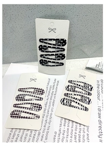 Detail of 12-piece drip hair clip set featuring checkerboard and zebra patterns on cards