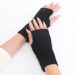 Macro detail of black knit fingerless gloves with a textured diamond cable stitch pattern