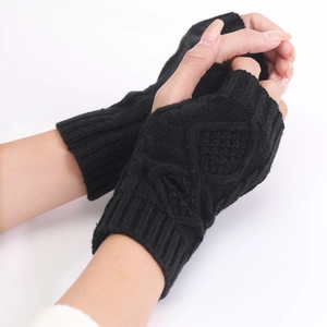 Detail of black cable-knit fingerless gloves showing diamond pattern and ribbed wrist cuff