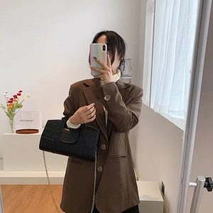 Mirror selfie showing a woman holding a black crocodile pattern handbag with gold chain