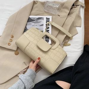 Detail of cream crocodile embossed handbag with square handle and gold chain strap