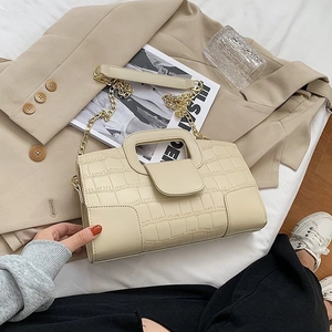 Detail of beige crocodile pattern bag with gold chain strap on professional model