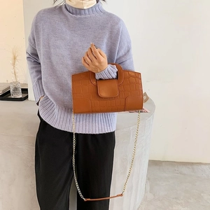 Detail of a brown crocodile pattern handbag with elegant gold chain strap for women