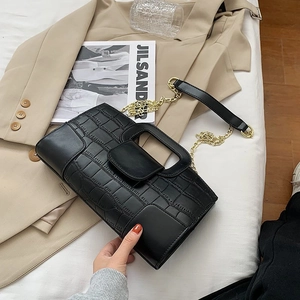 Detail of crocodile embossed handbag with gold chain strap and elegant top handle