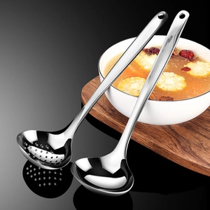 Polished stainless steel soup and slotted spoons displayed next to a fresh corn soup bowl
